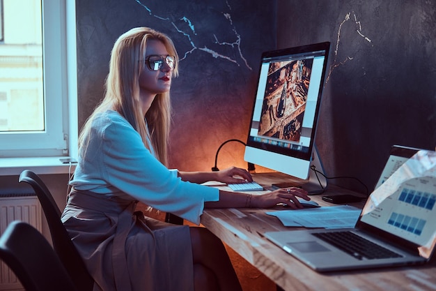 Una joven estudiante atractiva está trabajando en su nuevo proyecto en casa usando una computadora.