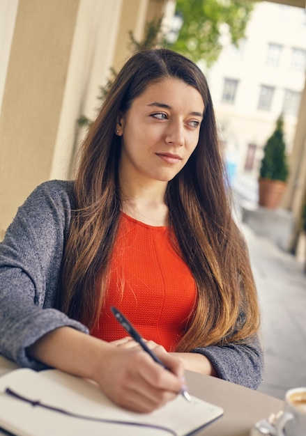 Joven estudiante atractiva con vestido rojo estudiando y leyendo un libro