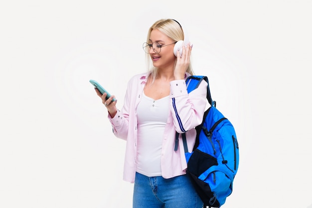 Joven estudiante en auriculares con mochila beber café, sonriendo. Startup, freelance. Aprender idiomas extranjeros en línea, preparación de exámenes