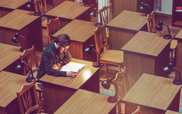 Joven estudiante barbudo leyendo en