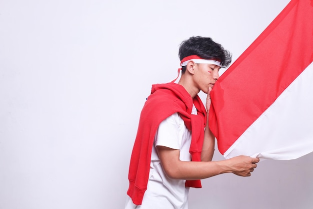 Foto joven estudiante besa el orgullo de la bandera indonesia para celebrar el día de la independencia