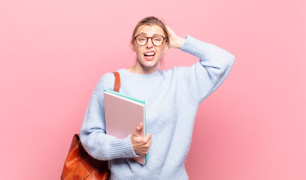 Joven estudiante bonita que se siente estresada, preocupada, ansiosa o asustada, con las manos en la cabeza, en pánico por el error