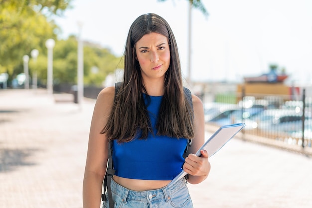 Foto joven estudiante brasileña al aire libre con expresión triste