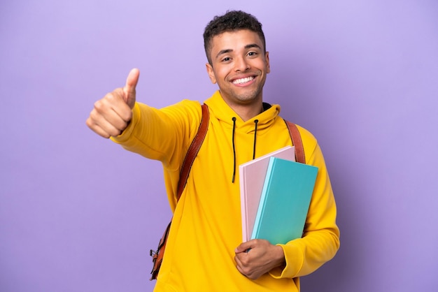 Joven estudiante brasileño hombre aislado sobre fondo púrpura dando un gesto de aprobación