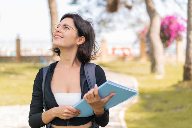 Joven estudiante búlgara al aire libre mirando hacia arriba mientras sonríe