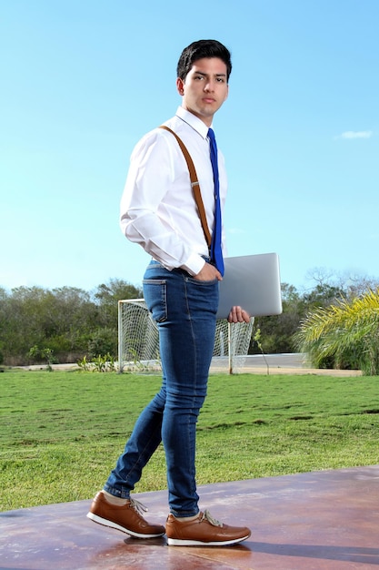 joven estudiante caminando con una computadora portátil en su mano creativa con una computadora portátil en el parque