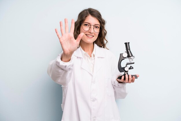 Joven estudiante científica de mujer bonita adulta con un microscopio