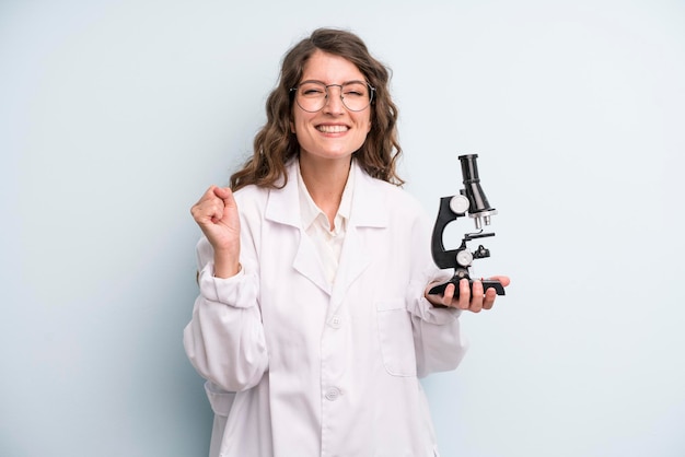 Joven estudiante científica de mujer bonita adulta con un microscopio