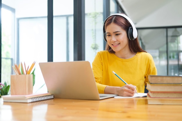 Joven estudiante de colegios usando computadora y dispositivo móvil estudiando en línea