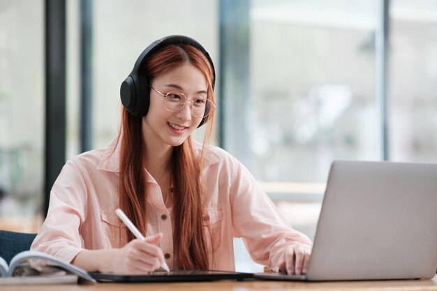 Joven estudiante de colegios usando computadora y dispositivo móvil estudiando en línea