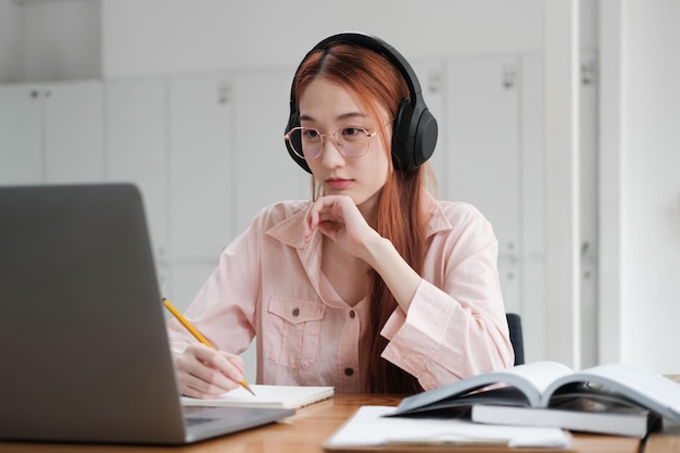 Joven estudiante de colegios usando computadora y dispositivo móvil estudiando en línea