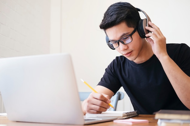 Joven estudiante de collage usando computadora y dispositivo móvil estudiando en línea. Educación y aprendizaje en línea.