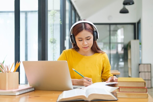 Joven estudiante de collage usando computadora y dispositivo móvil estudiando en línea