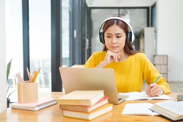 Joven estudiante de collage usando computadora y dispositivo móvil estudiando en línea