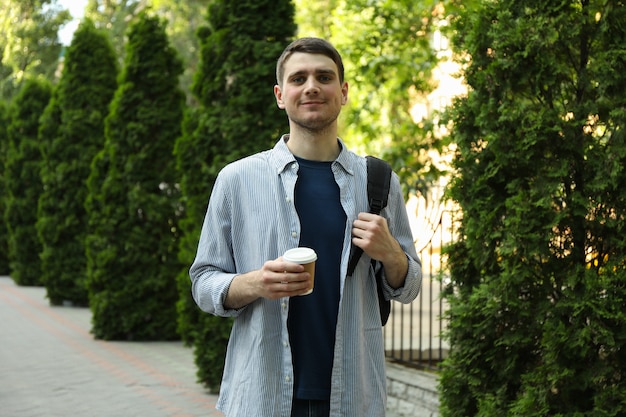 Joven estudiante espera mochila y taza de café.