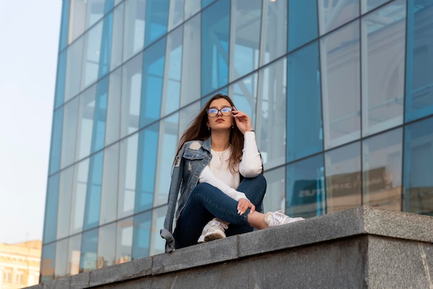 Joven estudiante está descansando en la calle de la ciudad Mujer elegante joven en ropa juvenil de moda