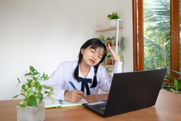 Joven estudiante estudia en casa con laptop