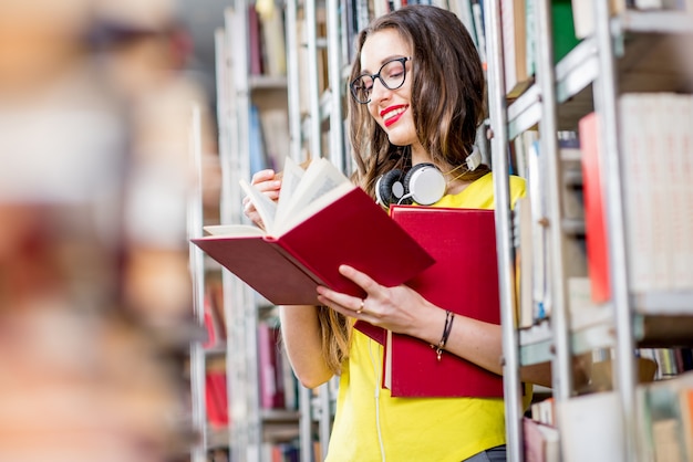 Joven estudiante feliz y entusiasta leyendo libros en la antigua biblioteca