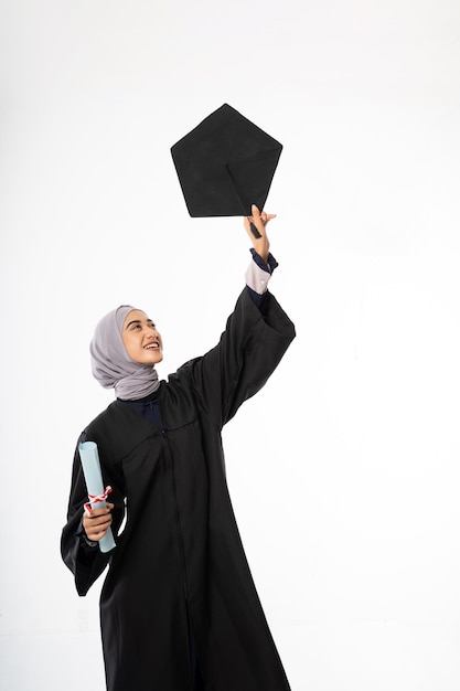 Joven estudiante graduada en toga sosteniendo un sombrero de pizarra