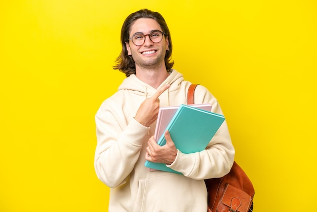 Joven estudiante guapo aislado de fondo amarillo apuntando hacia un lado para presentar un producto