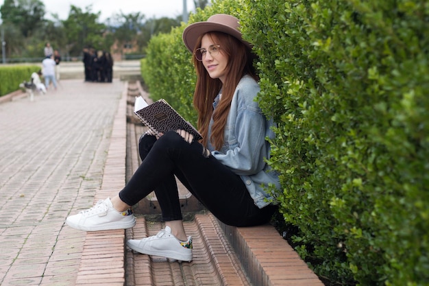 Foto joven estudiante hermosa leyendo un libro en un parque en una biblioteca universitaria