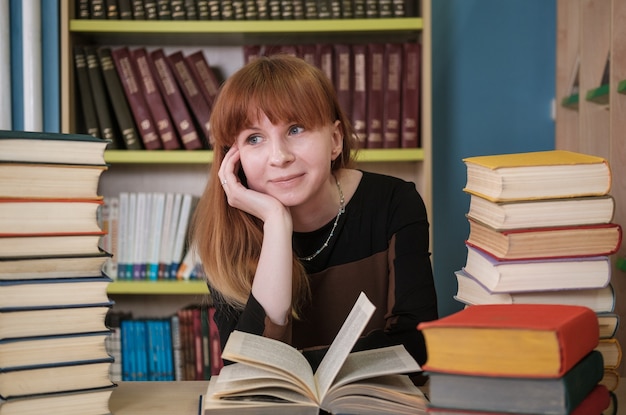 Joven estudiante hermosa trabaja con libros en la biblioteca.