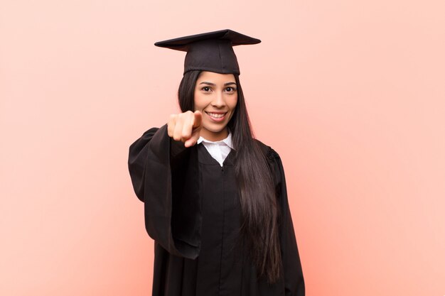 Joven estudiante latina señalando con una sonrisa satisfecha, segura y amigable, eligiéndote