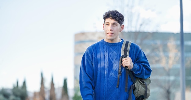 Joven estudiante latinoamericano caminando fuera del edificio del campus universitario