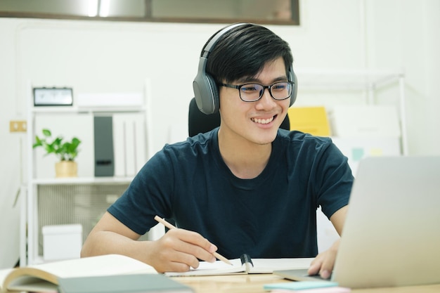 Joven estudiante masculino estudia en casa Él usa una computadora portátil y aprende en líneaxD