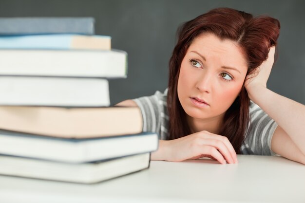 Joven estudiante mirando la cantidad de libros que tiene que leer