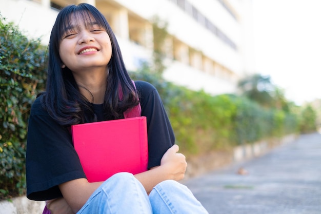 Joven estudiante con mochila rosa sentada en el suelo con antecedentes escolares.