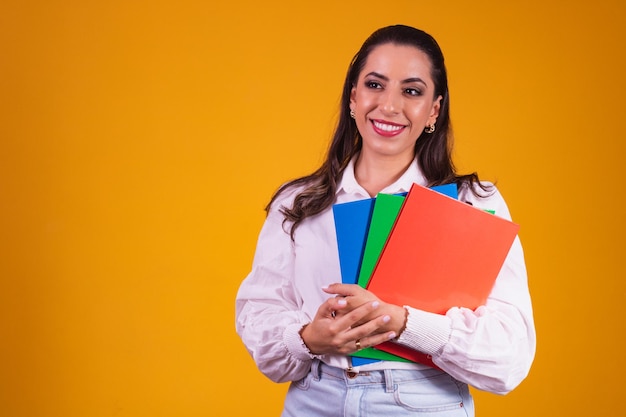 Joven estudiante morena con cuadernos en las manos. estudiante universitario sonriendo a la cámara