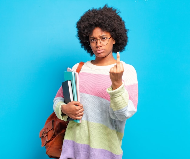 Joven estudiante mujer afro que se siente enojada, molesta, rebelde y agresiva, moviendo el dedo medio, contraatacando