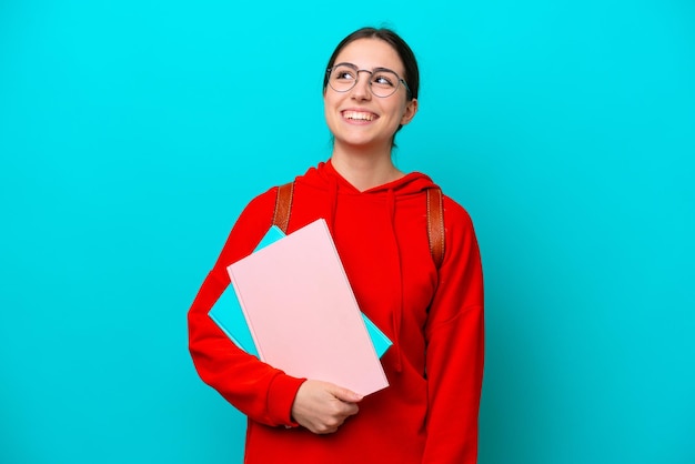 Joven estudiante mujer caucásica aislada de fondo azul pensando en una idea mientras mira hacia arriba