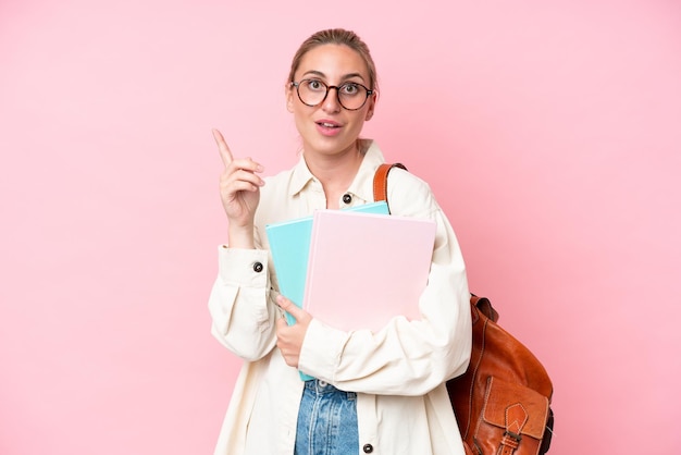 Joven estudiante mujer caucásica aislada de fondo rosa con la intención de darse cuenta de la solución mientras levanta un dedo