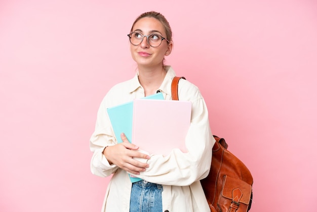 Joven estudiante mujer caucásica aislada de fondo rosa pensando en una idea mientras mira hacia arriba