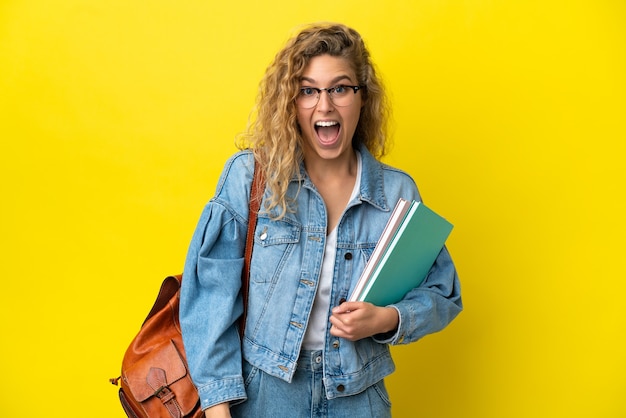 Joven estudiante mujer caucásica aislada sobre fondo amarillo con expresión facial sorpresa