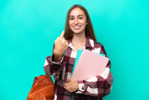 Joven estudiante mujer caucásica aislada sobre fondo azul haciendo el gesto de venir