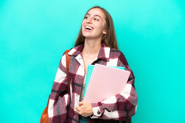 Joven estudiante mujer caucásica aislada sobre fondo azul riendo