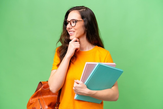 Foto joven estudiante mujer caucásica sobre fondo aislado mirando a un lado y sonriendo