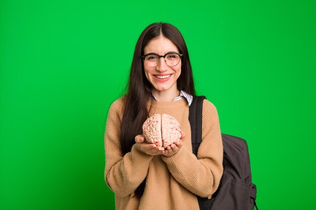 Joven estudiante mujer caucásica sosteniendo un cerebro aislado