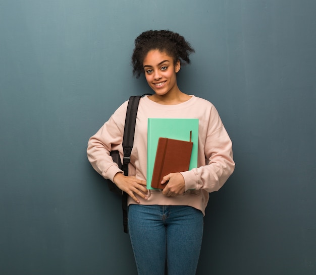 Joven estudiante mujer negra con las manos en las caderas. Ella tiene libros.