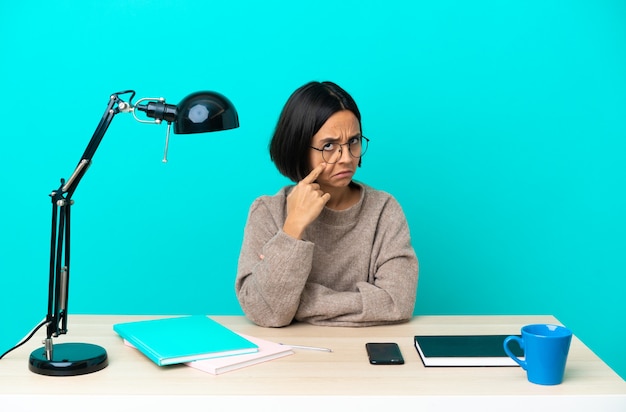 Joven estudiante mujer de raza mixta estudiando sobre una mesa mostrando algo