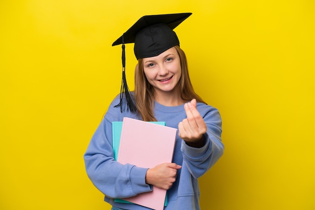 Joven estudiante mujer rusa aislada de fondo amarillo haciendo gesto de dinero