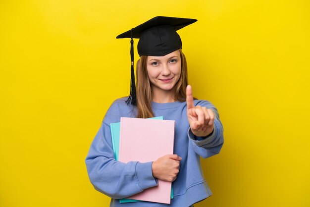 Joven estudiante mujer rusa aislada de fondo amarillo mostrando y levantando un dedo