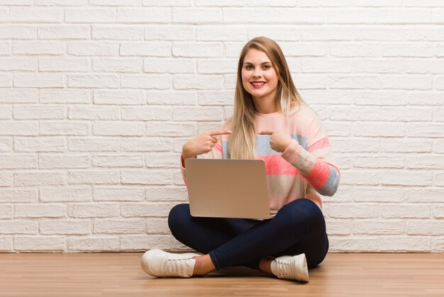 Joven estudiante mujer sentada sorprendida, se siente exitosa y próspera