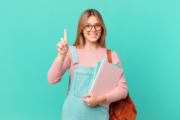 joven estudiante mujer sonriendo y luciendo amigable, mostrando el número uno