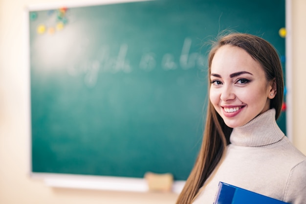 Joven estudiante o profesor sonriente en la pizarra