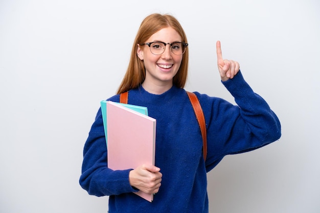 Joven estudiante pelirroja mujer aislada sobre fondo blanco apuntando hacia una gran idea