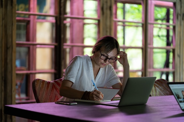 Una joven estudiante pensativa y enfocada sentada con una laptop caucásica trabajando en un espacio de coworking